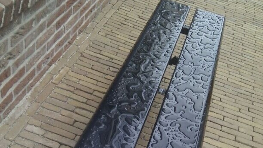 In between this fake buildings, the waterpatterns on an iron bench suddenly are of utmost beauty