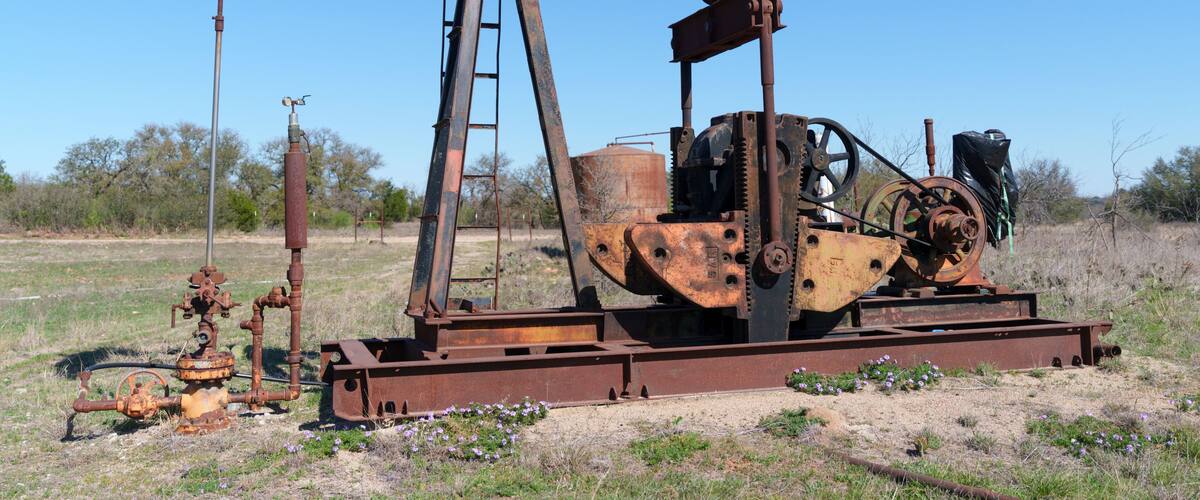 Idle, rusty oil well pump jack abandoned in field in West Texas.