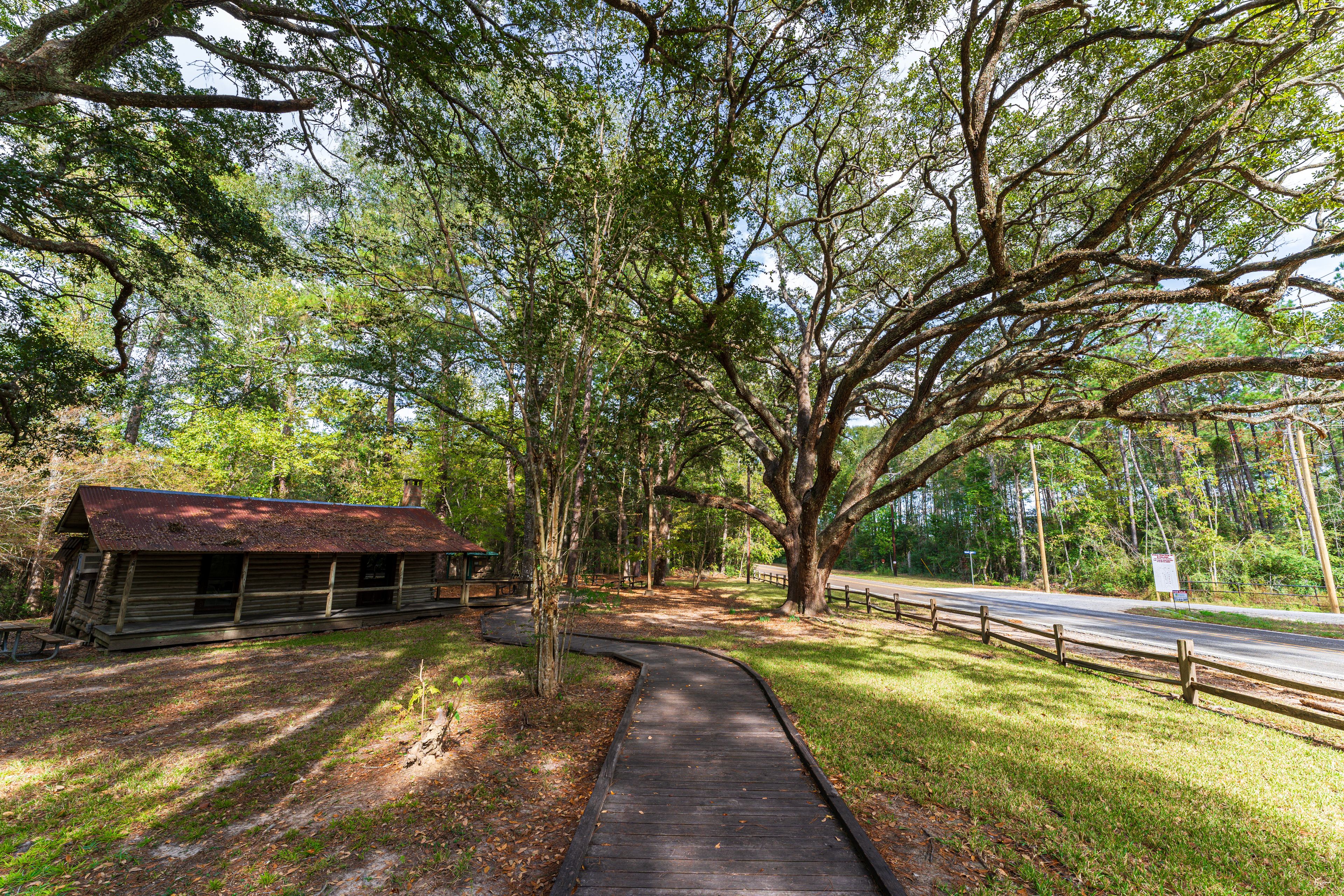 A wooden cabin, a paved walkway, and a road with a guardrail.