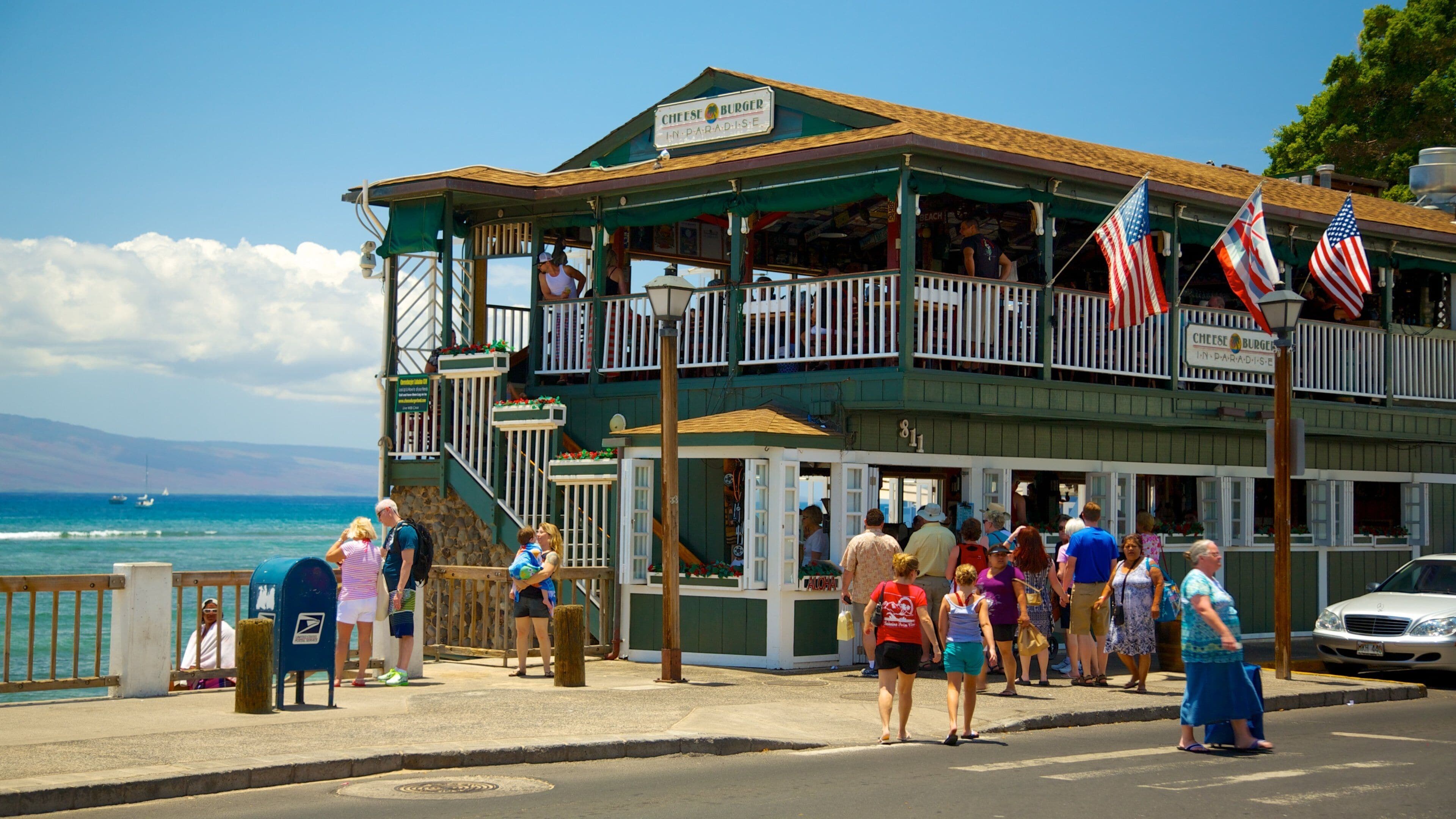 A coastal restaurant with a view of the ocean, a balcony, and American flags.