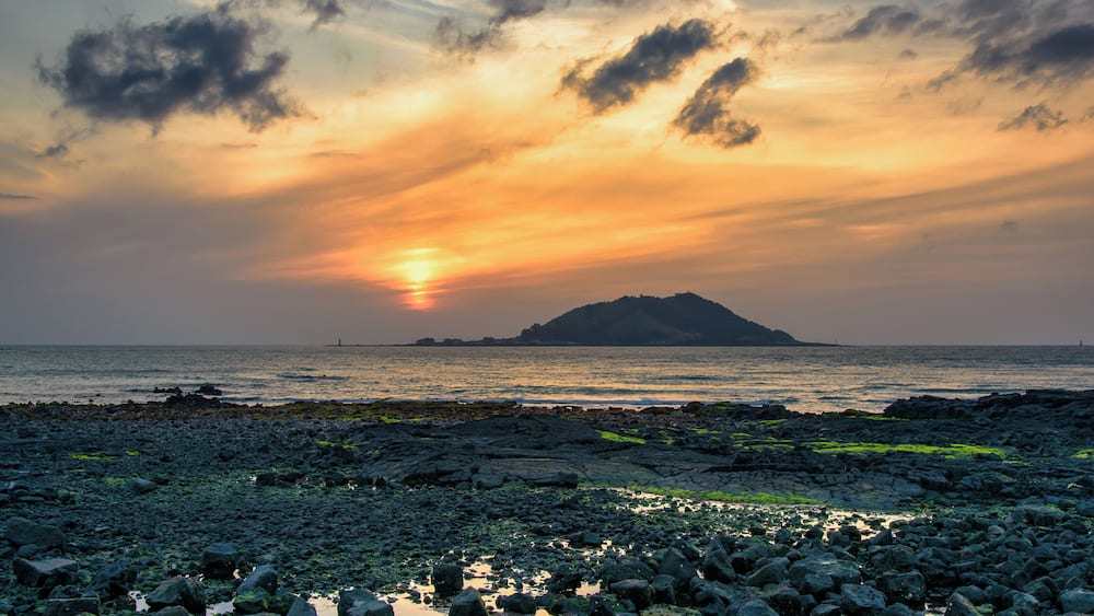 Sunset with Biyangdo island in a cloudy day, view from Hyeopjae beach in Aewol in Jeju Island, Korea.