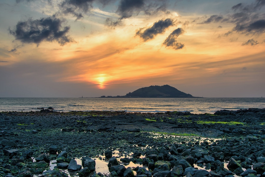 Sunset with Biyangdo island in a cloudy day, view from Hyeopjae beach in Aewol in Jeju Island, Korea.