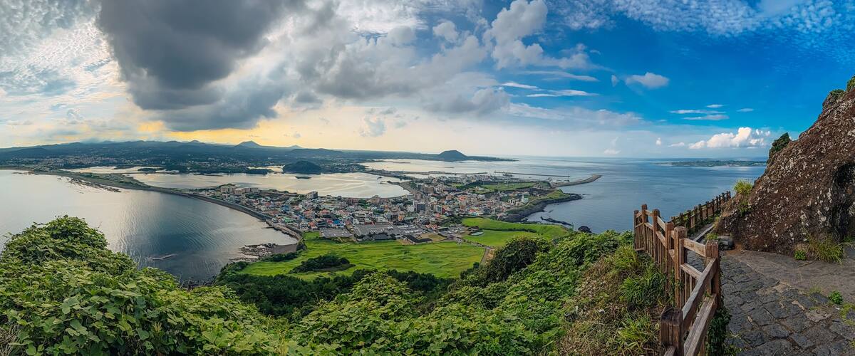 A coastal city with a large bay, surrounded by mountains and greenery.