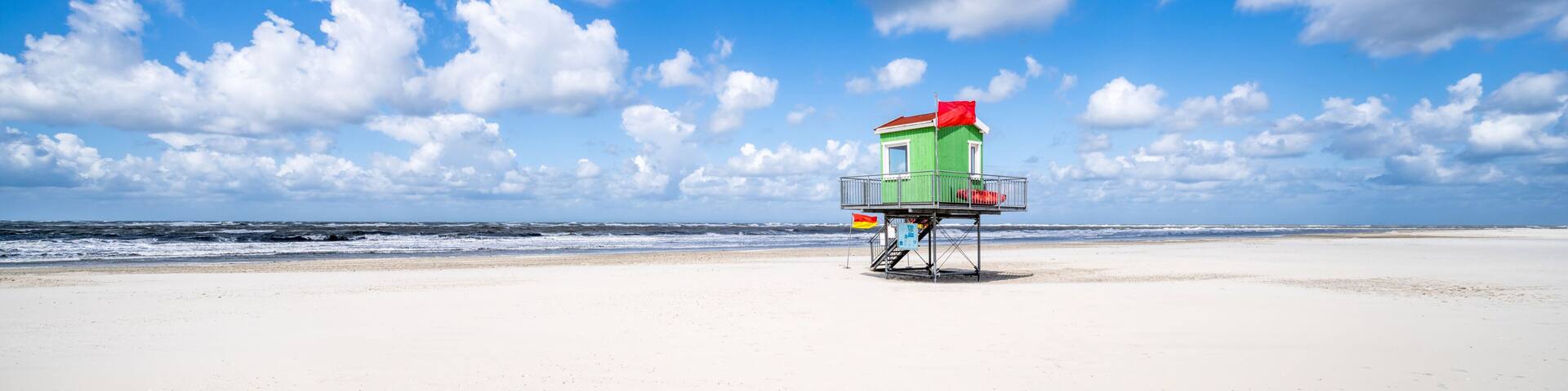 A lifeguard tower on a beach with a clear sky and ocean waves.