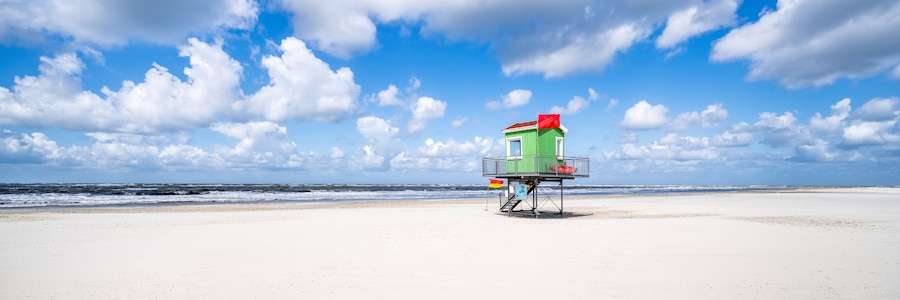 Een redder uitkijktoren op een strand met heldere lucht en golven in de zee.