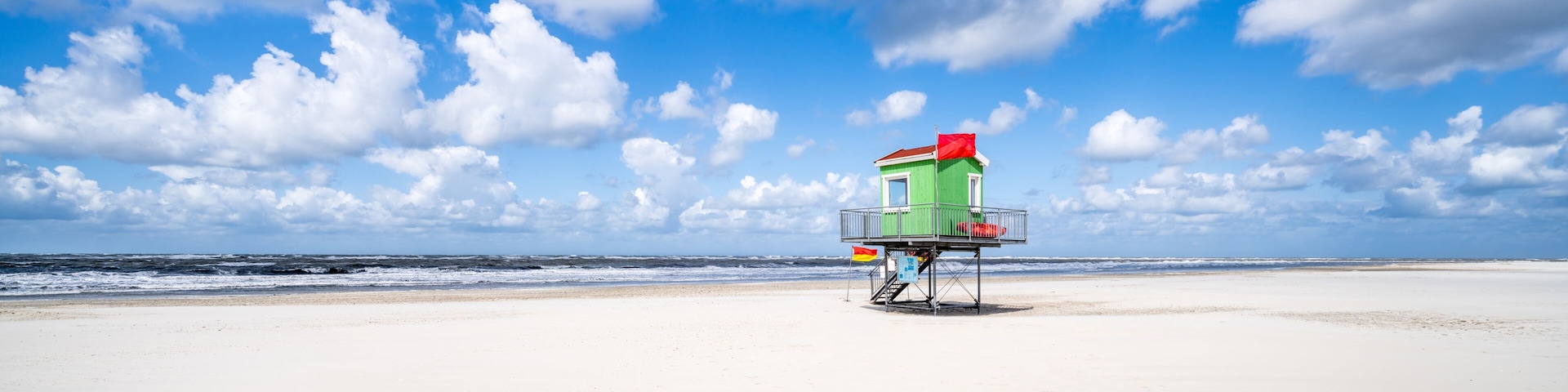 A lifeguard tower on a beach with a clear sky and ocean waves.