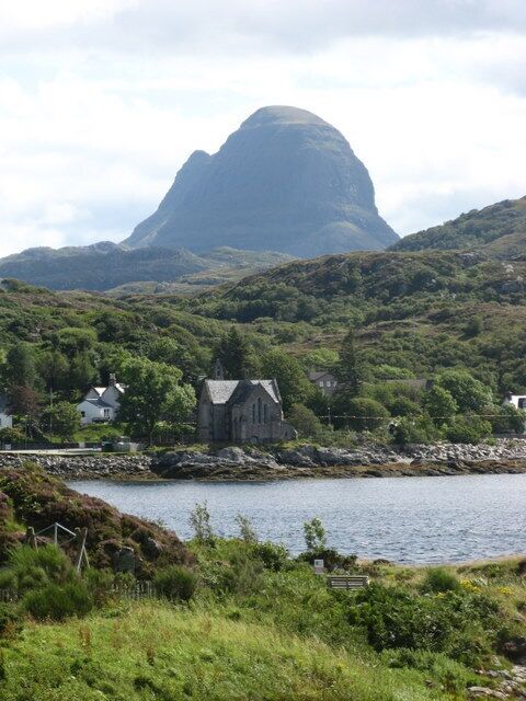 A coastal landscape with a prominent mountain, a church, and a body of water.