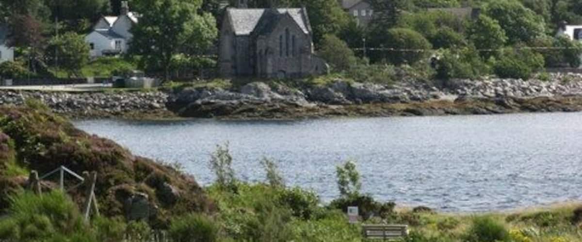 Een kustlandschap met een opvallende berg, een kerk en een waterpartij.