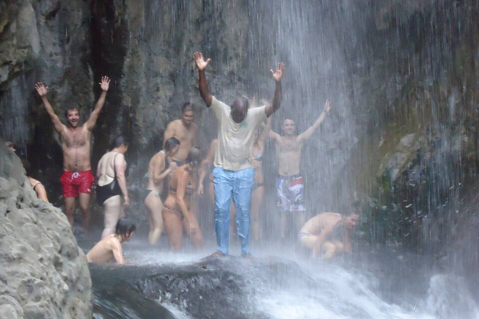 A group of people enjoying a waterfall in a rocky, natural setting.