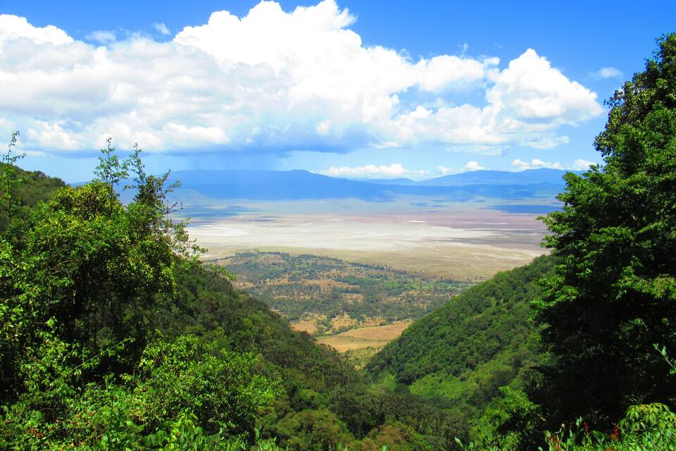 A valley with lush greenery and distant mountains under a partly cloudy sky.