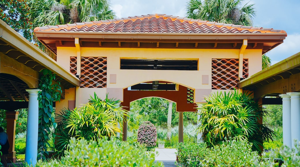 A traditional pavilion with terracotta roof tiles, surrounded by lush greenery and palm trees.