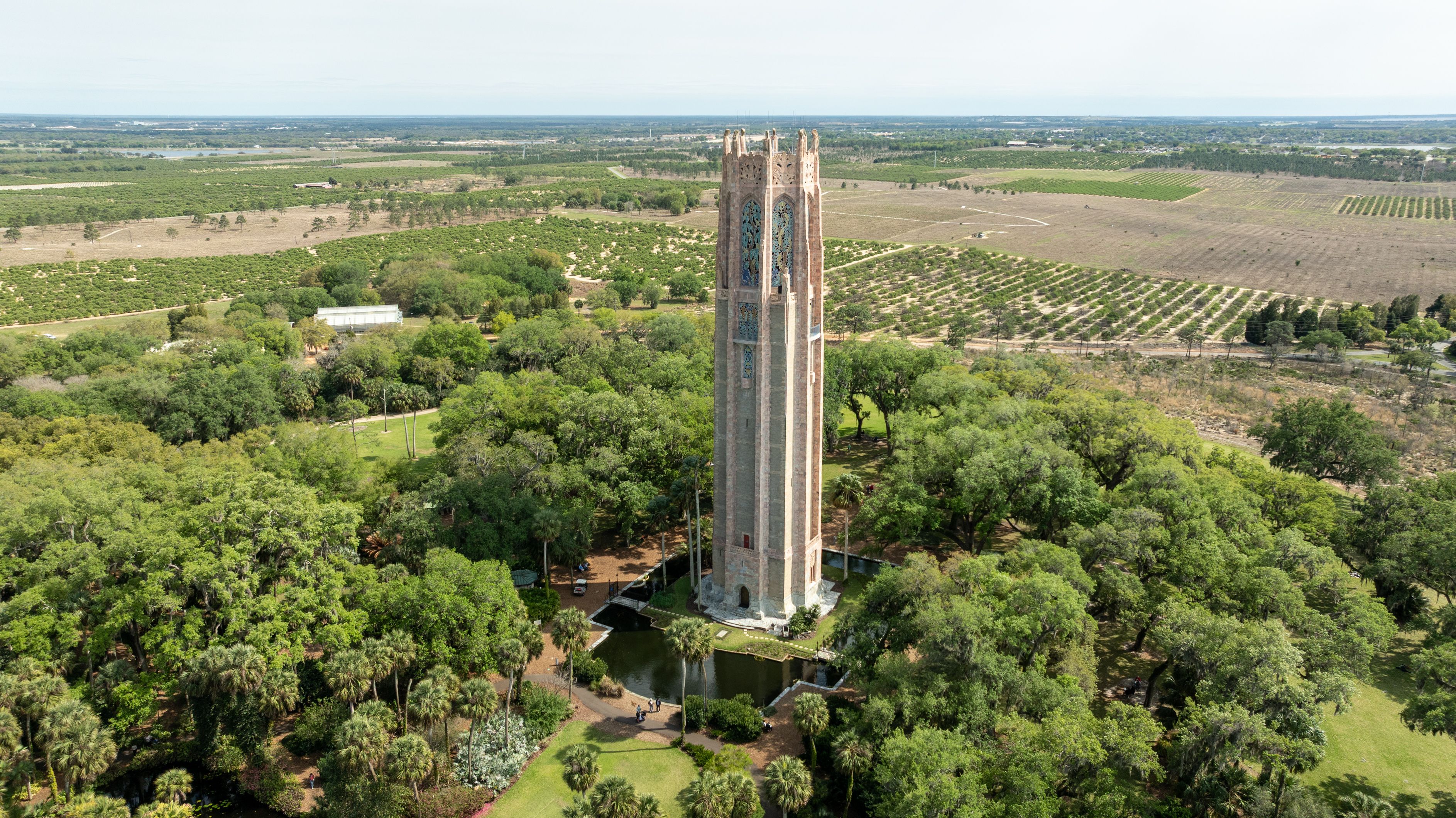 A tall tower surrounded by lush greenery and fields.