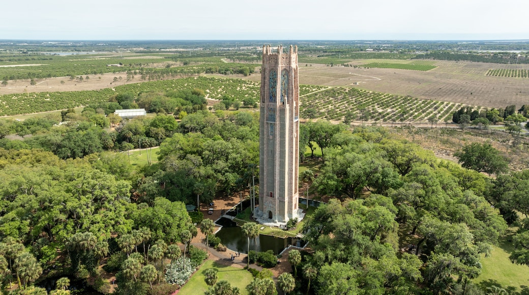 A tall tower surrounded by lush greenery and fields.