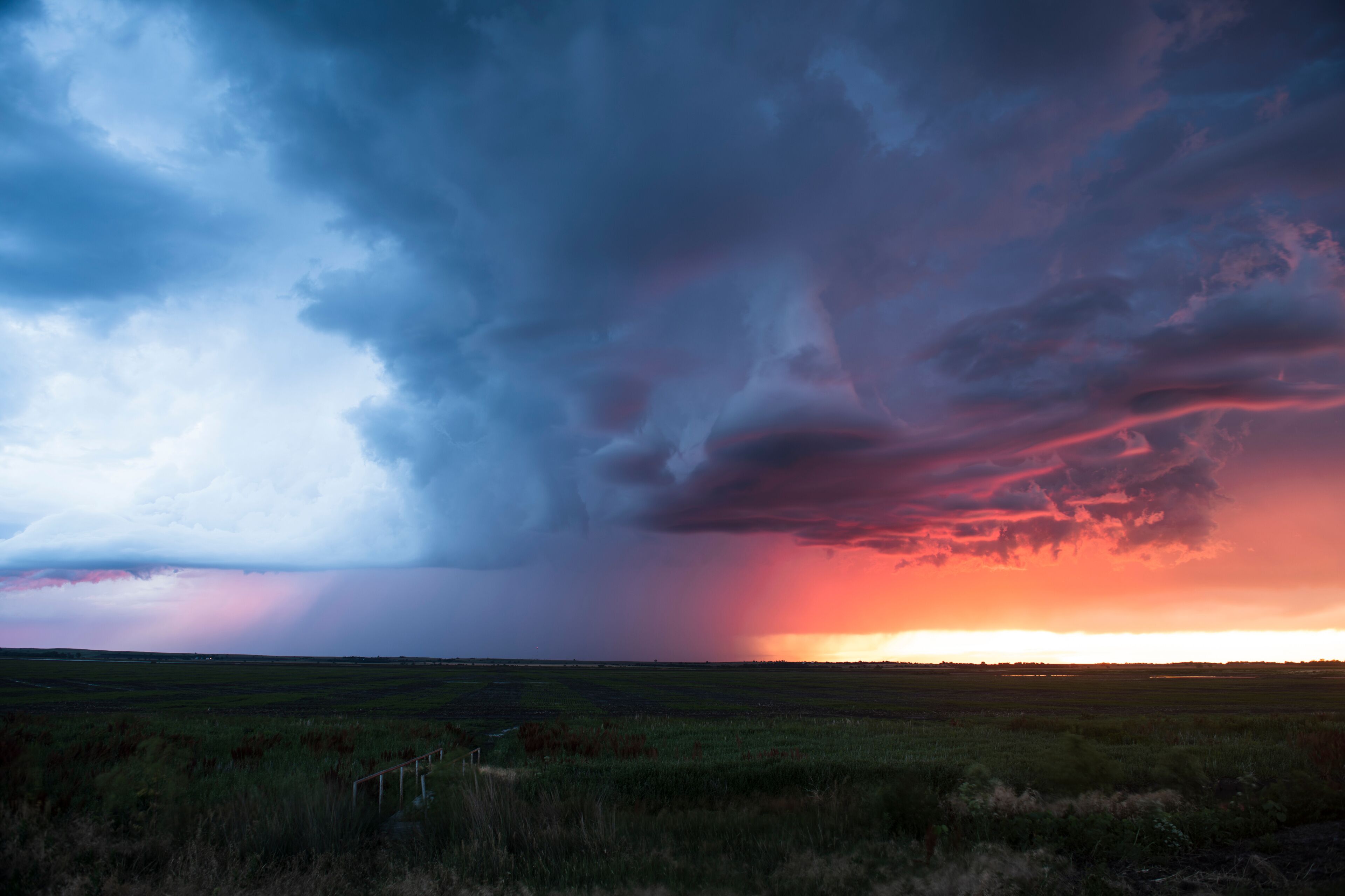 Un extenso campo abierto bajo un cielo espectacular con un atardecer.