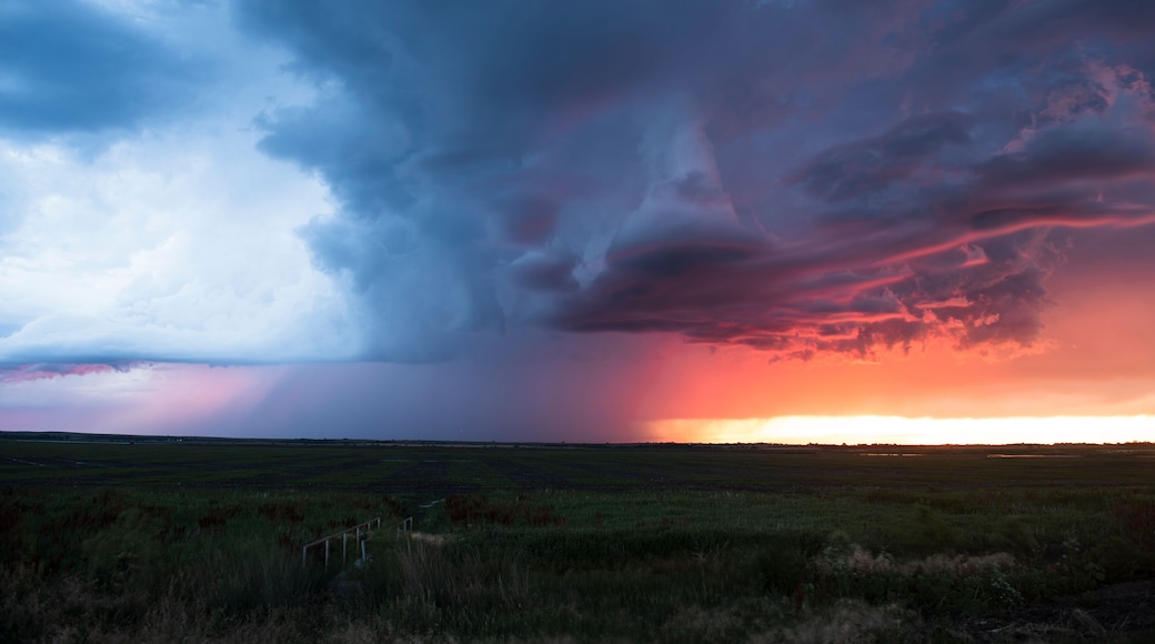 Un extenso campo abierto bajo un cielo espectacular con un atardecer.