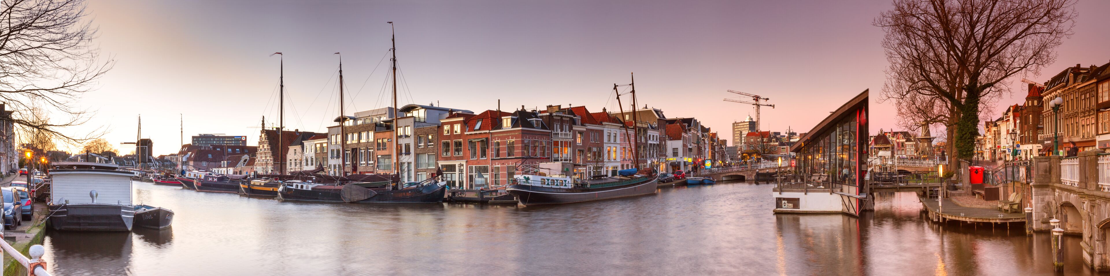 A canal with boats docked, historic buildings, and a bridge.