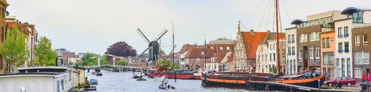 A canal with boats, windmills, and historic buildings along the water.