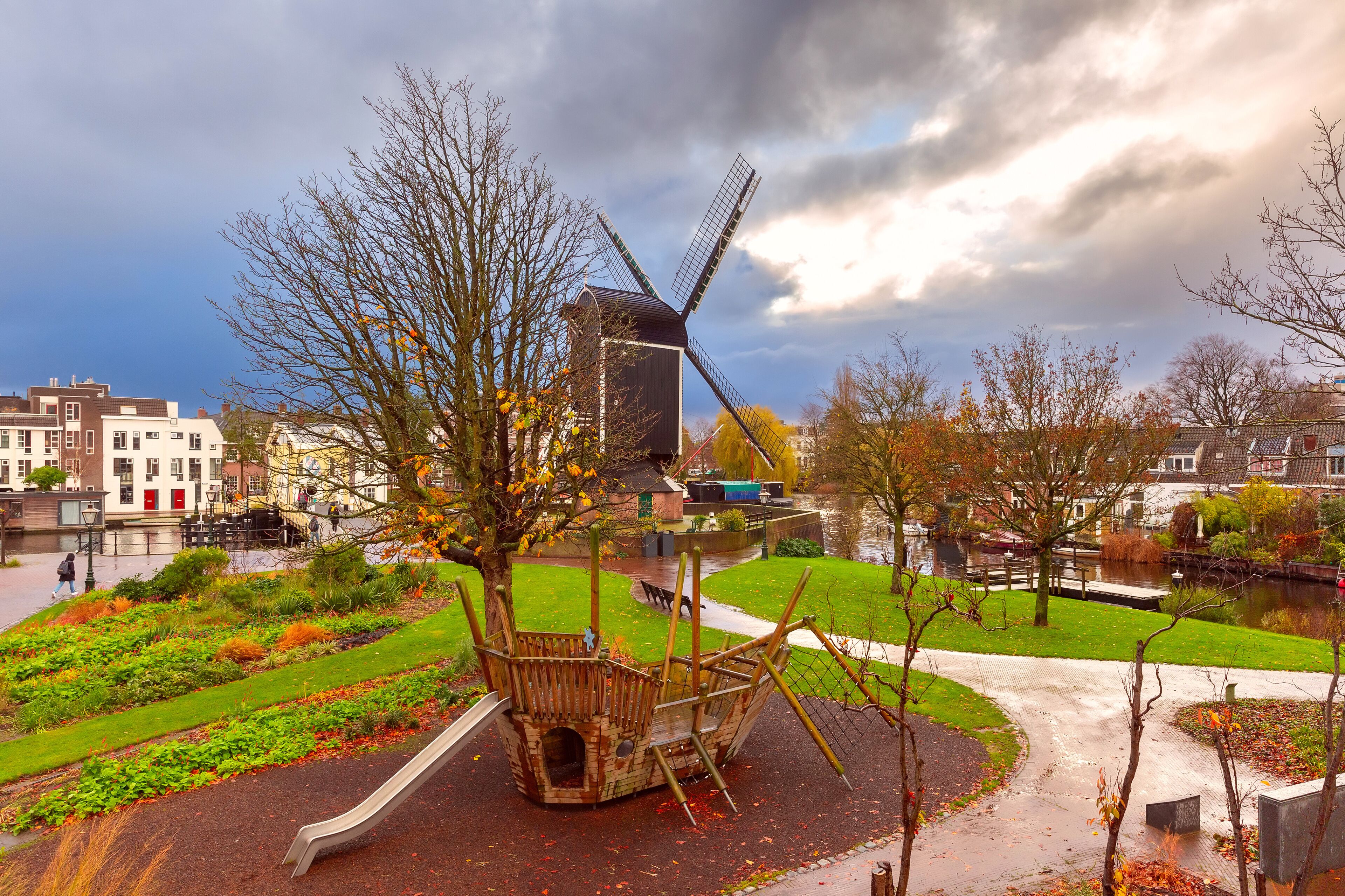 A park with a windmill, a canal, and a playground.