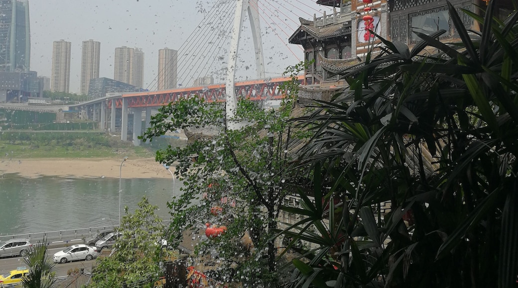China is a land of contrast. Although parts of Hongya Cave are a recreation, the site boasts 2300 years of history. The stilted building is accessible from three roads on three different floors. Across the Jianglin River, the site is mirrored by modern high-rise buildings. A suspension bridge spans the river between Old and New. The view here is obtained from walking behind the waterfall on the west side of the building.