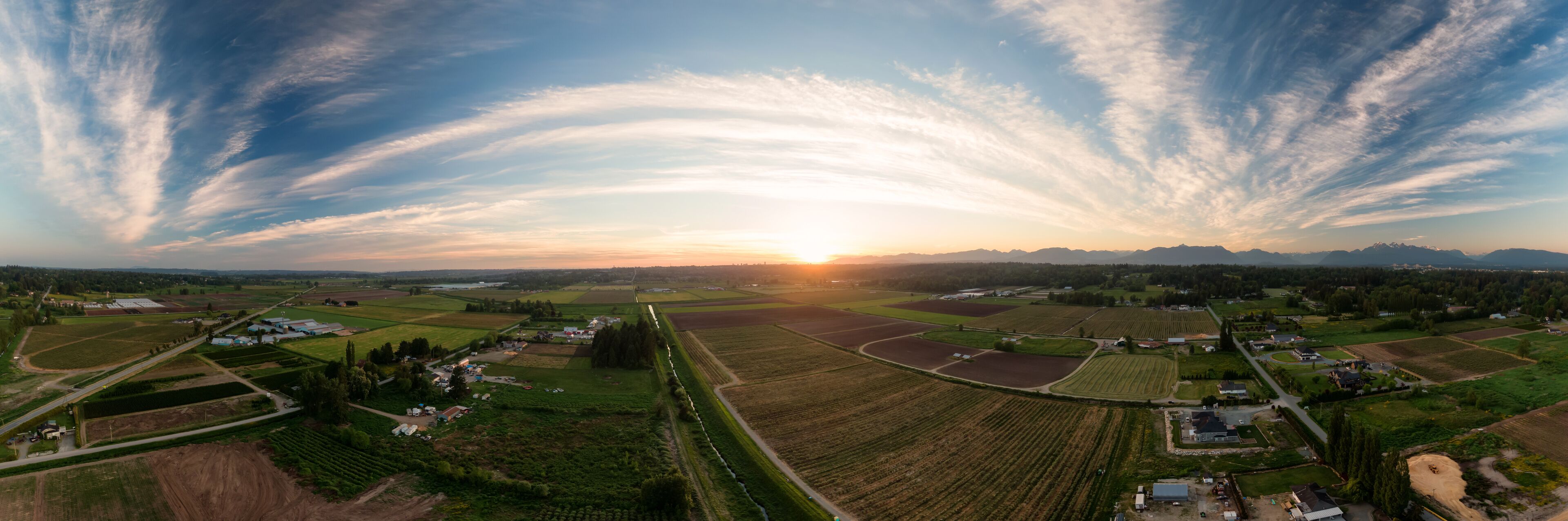 Aerial Panoramic View of Farm Fields in Fraser Valley during colorful Sunset. Taken in Langley, Greater Vancouver, British Columbia, Canada.