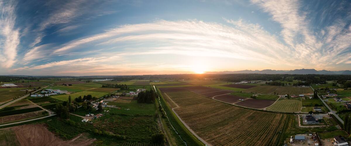 Aerial Panoramic View of Farm Fields in Fraser Valley during colorful Sunset. Taken in Langley, Greater Vancouver, British Columbia, Canada.