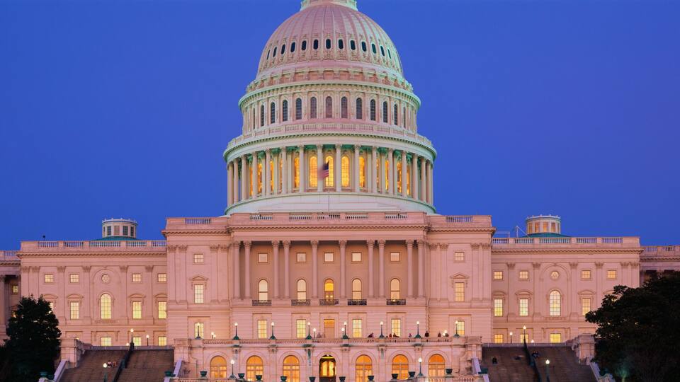A large, illuminated capitol building with a prominent dome and classical architecture.