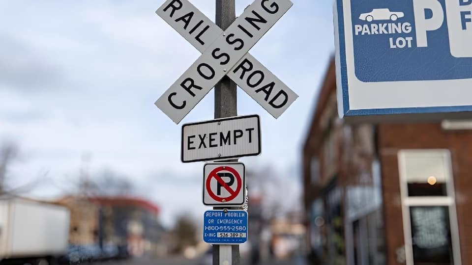 A street lamp with railroad crossing signs, a no parking sign, and a parking lot sign.