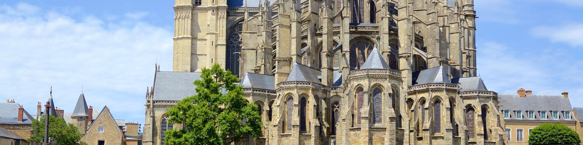 Una catedral histórica con arquitectura gótica intrincada, una imponente torre de reloj y un muro de piedra que rodea el lugar.