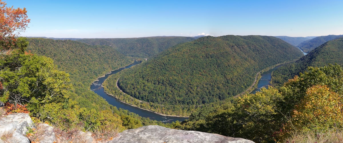 A river winding through a forested valley with mountains in the background.
