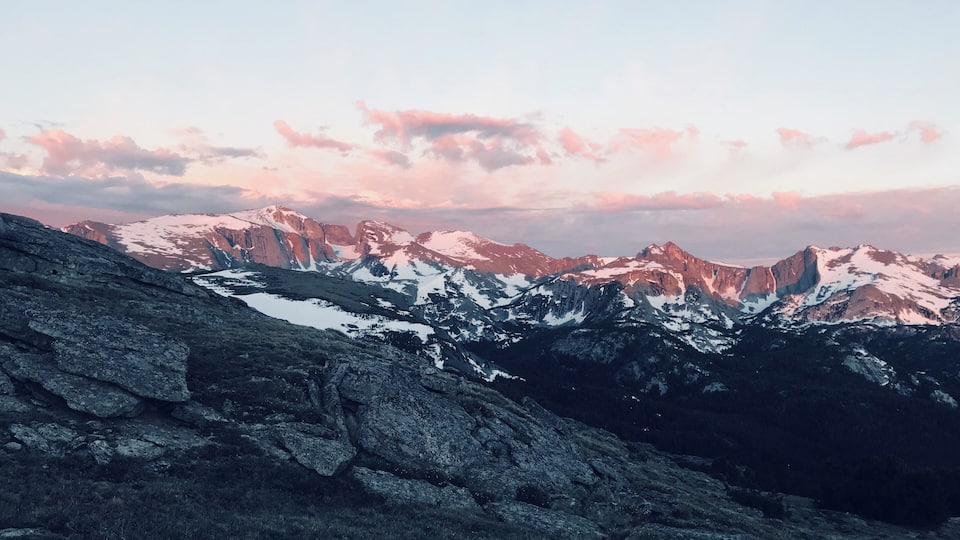 A mountain range with snow-capped peaks and a rocky foreground.