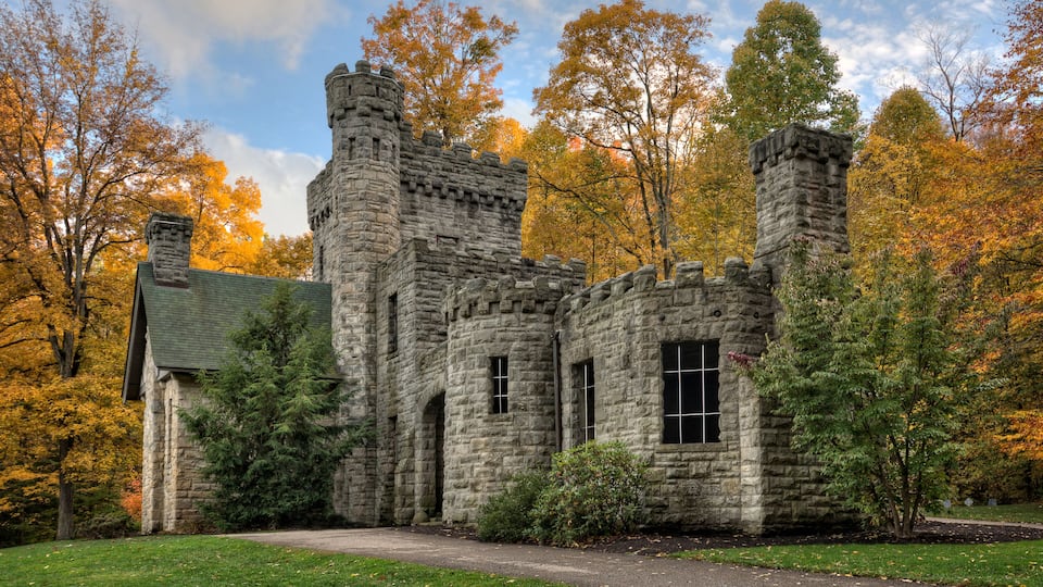 A historic stone building with turrets surrounded by autumn foliage.