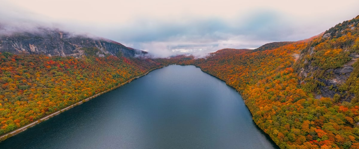 A river surrounded by autumn-colored trees and mountains.