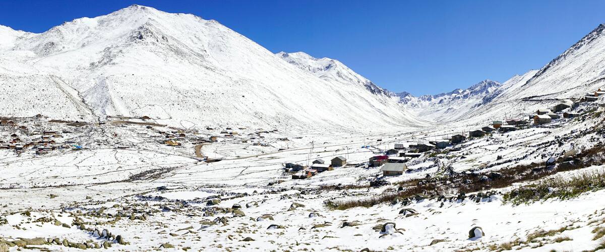 A snow-covered mountain landscape with a village nestled in a valley.
