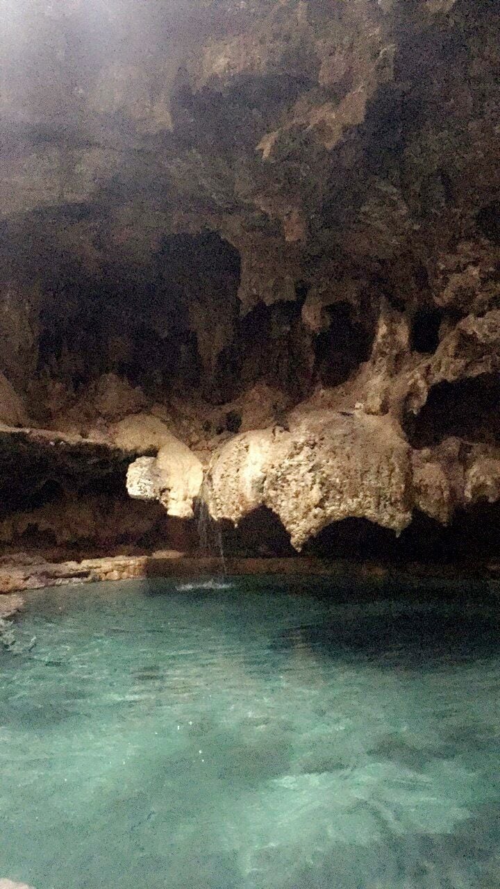 A cave with a clear pool at the bottom.