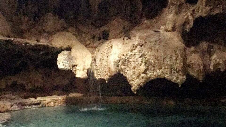 A cave with a clear pool at the bottom.