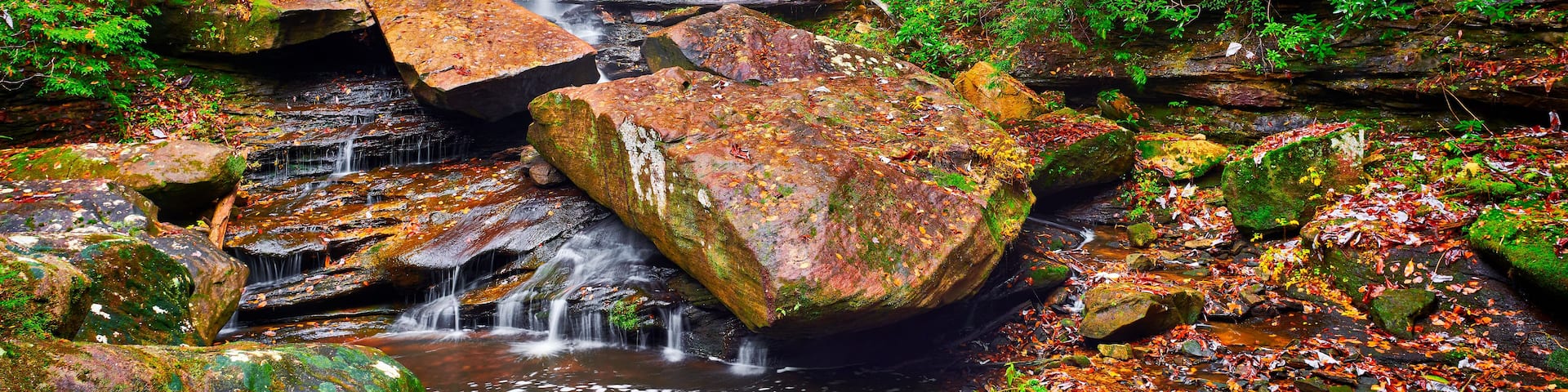 A waterfall cascading over rocks in a forested area.
