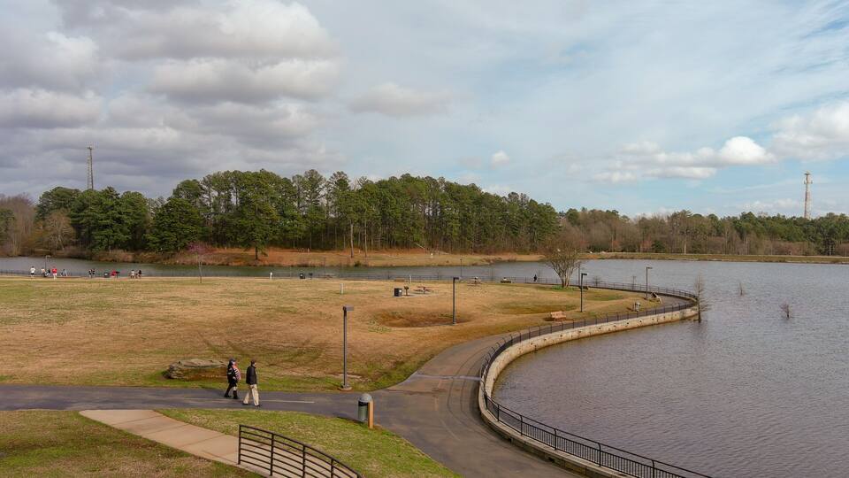 A lakeside park with walking paths, benches, and picnic areas.