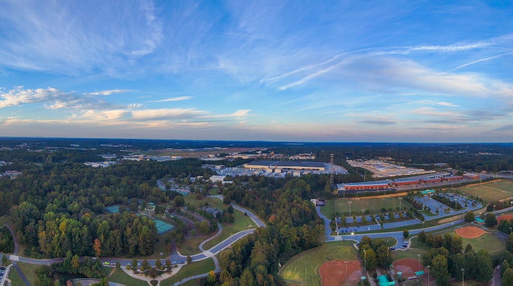 a stunning panoramic aerial shot of vast miles of lush green and autumn colored trees, still blue lake waters and blue sky with powerful cloud formations at Rhodes Jordan Park At Lawrenceville Lake in