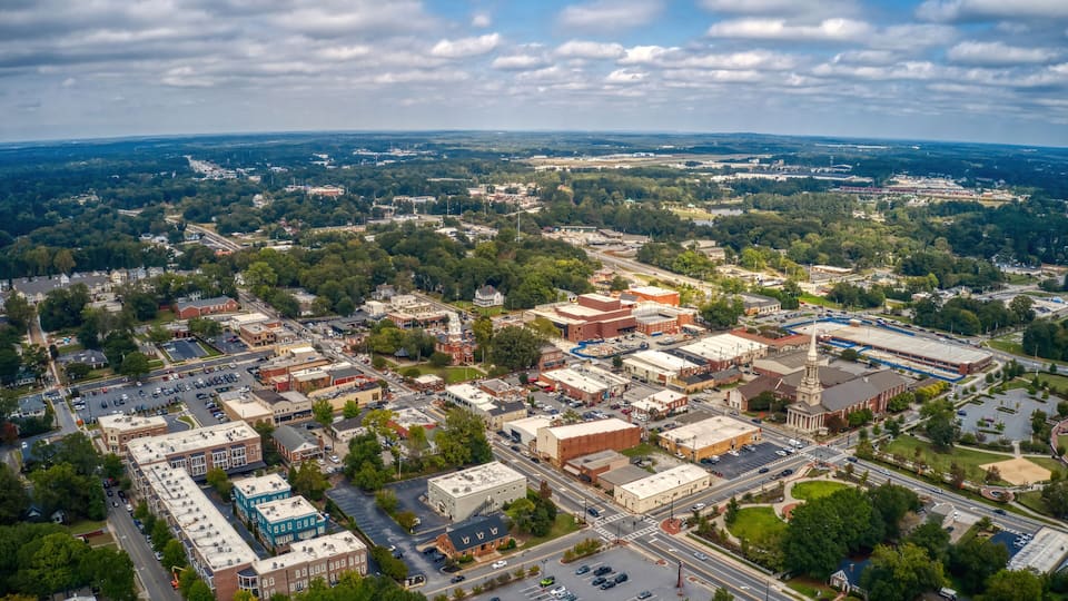 An aerial view of a town with a mix of commercial and residential buildings, a prominent church with a steeple, and a large industrial area.