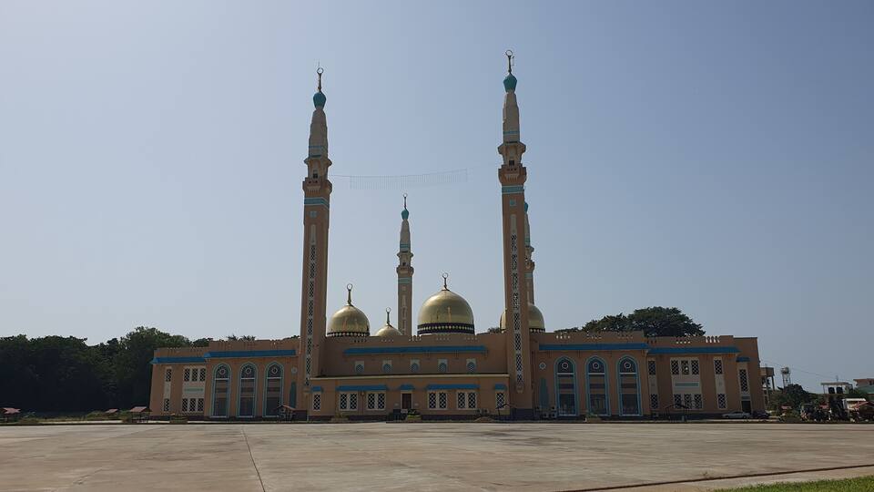 A large mosque with three tall minarets and golden domes.