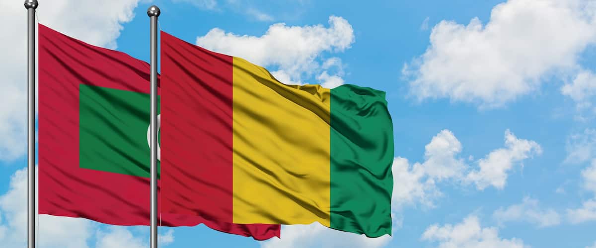 Two flags waving against a blue sky with clouds.