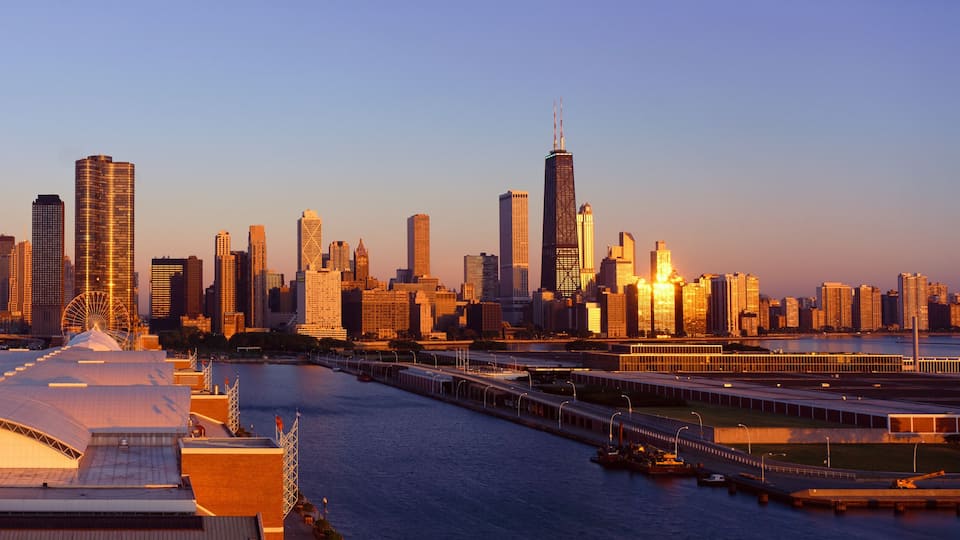 A city skyline with a prominent Ferris wheel and a river in the foreground.