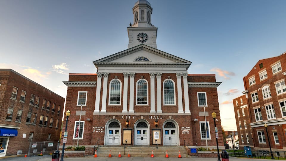 A historic building with a clock tower, named "City Hall," featuring arched windows and a prominent entrance.