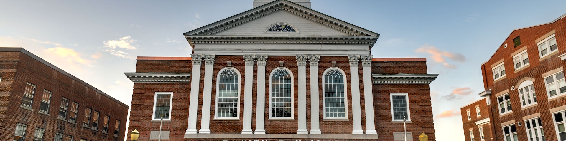 A historic building with a clock tower, named "City Hall," featuring arched windows and a prominent entrance.