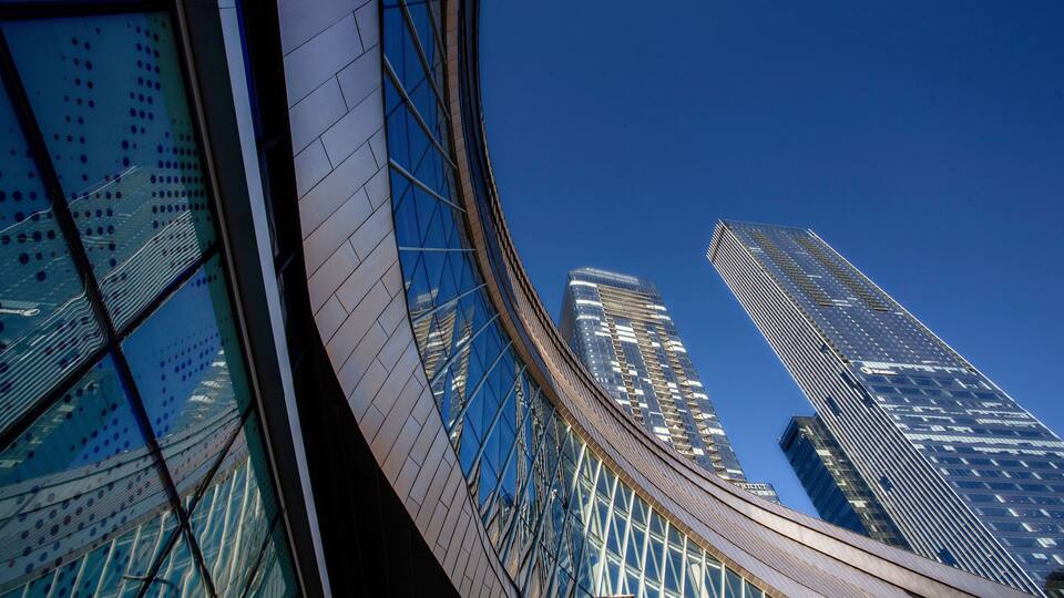 A modern glass building with a curved facade and a clear blue sky.
