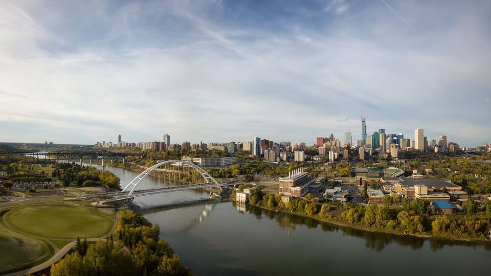 A river with a bridge, a city skyline, and a park.