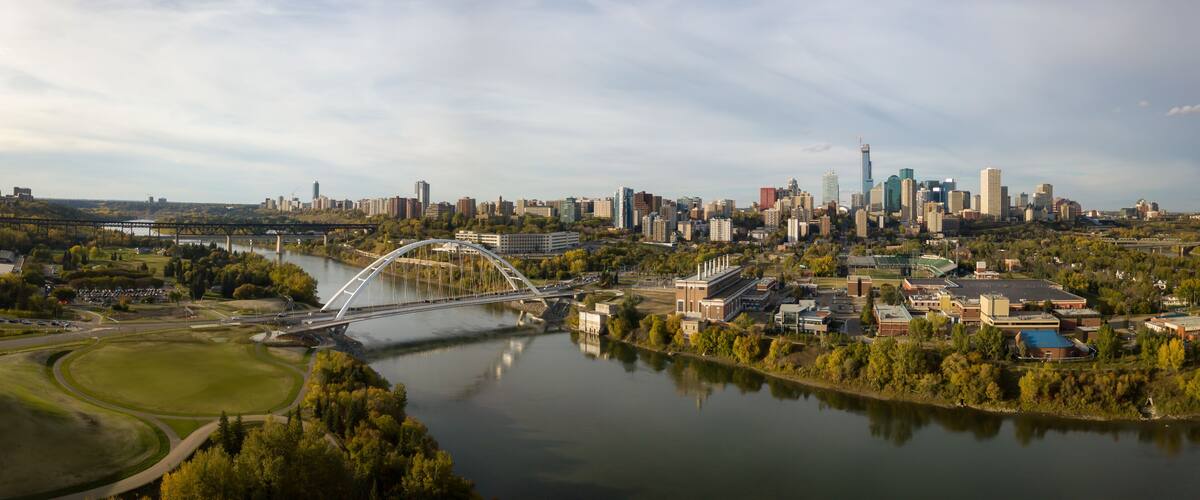 A river with a bridge, a city skyline, and a park.