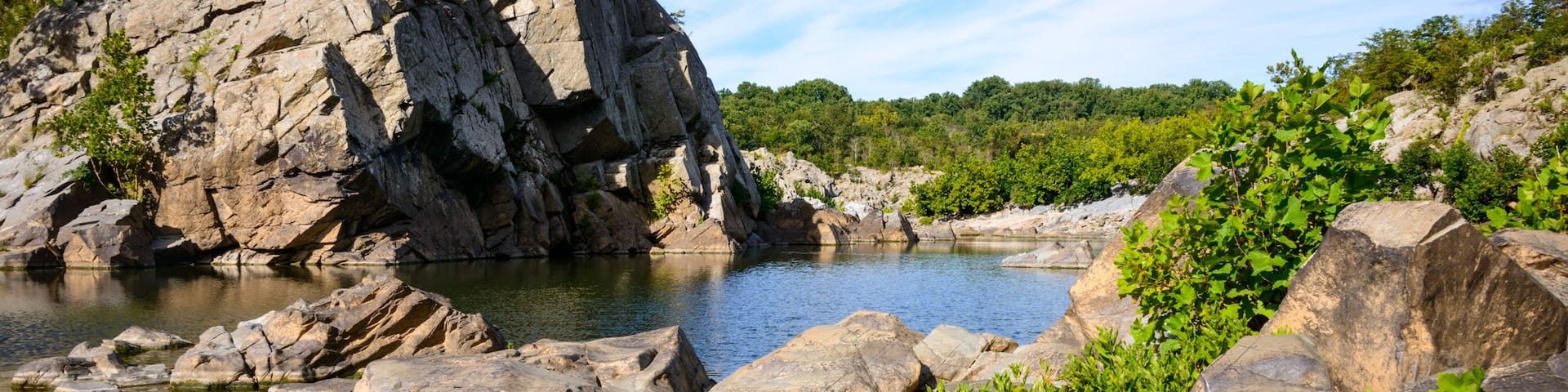 A rocky riverbank with large boulders and a calm river.
