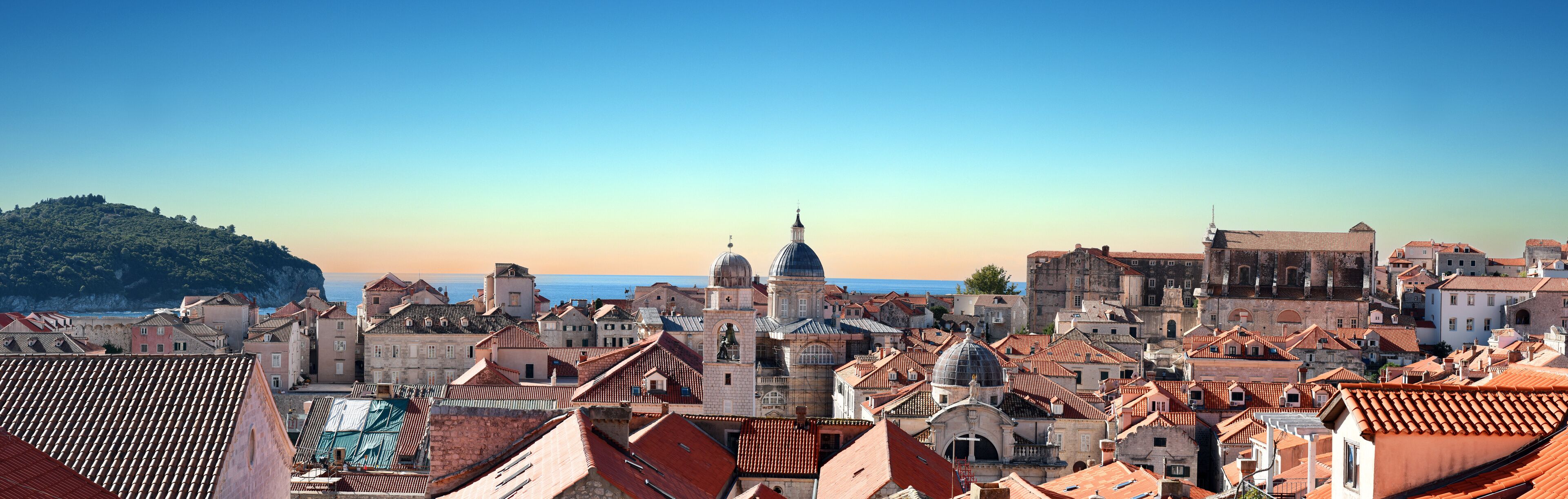 A coastal cityscape with historic buildings and a prominent church with a dome.