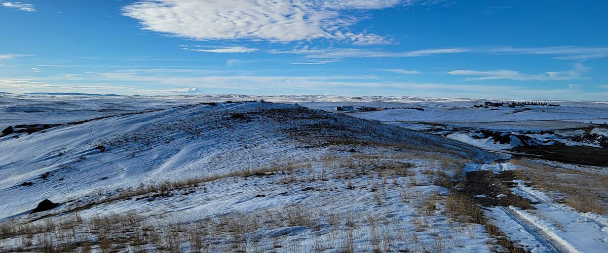 A snowy landscape with rolling hills and a clear blue sky.